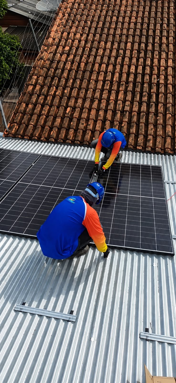 Técnicos JS Energy parafusando painel solar em telhado